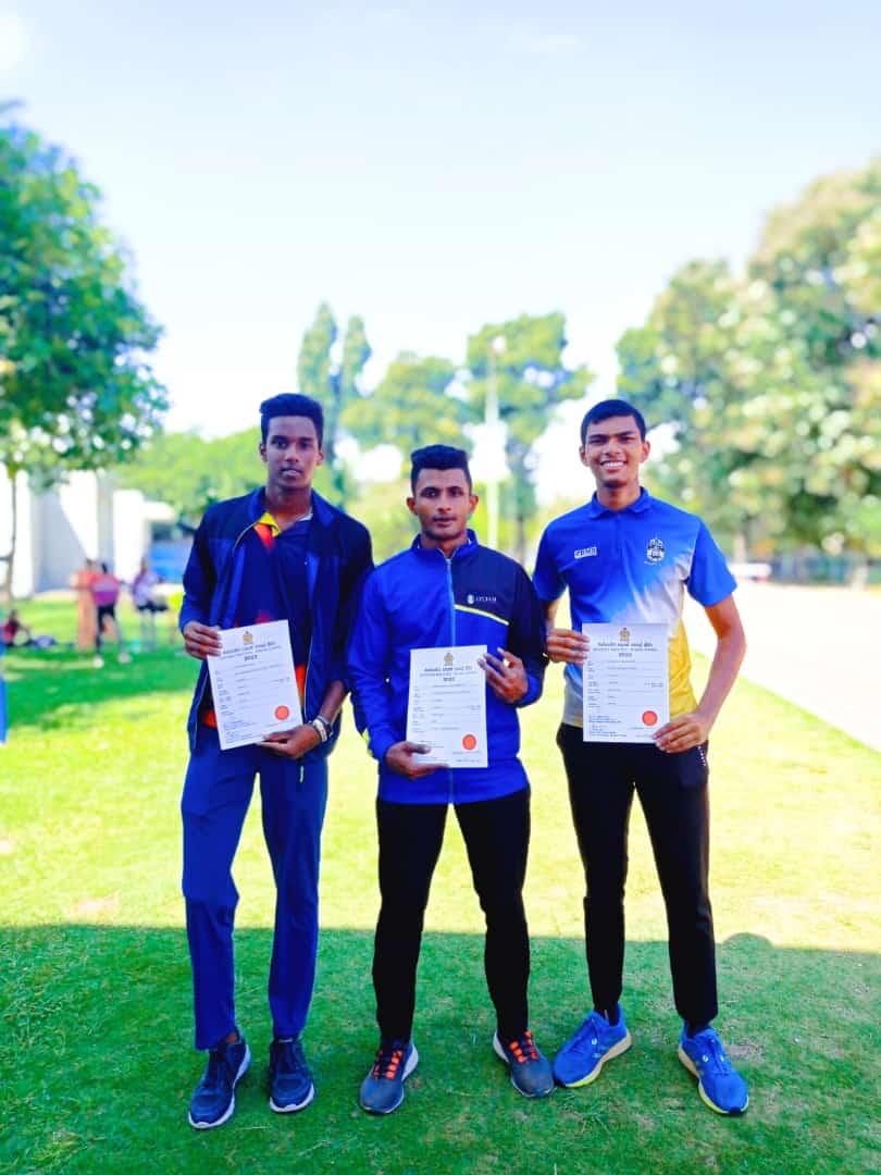Young men with certificates on a sunny lawn.