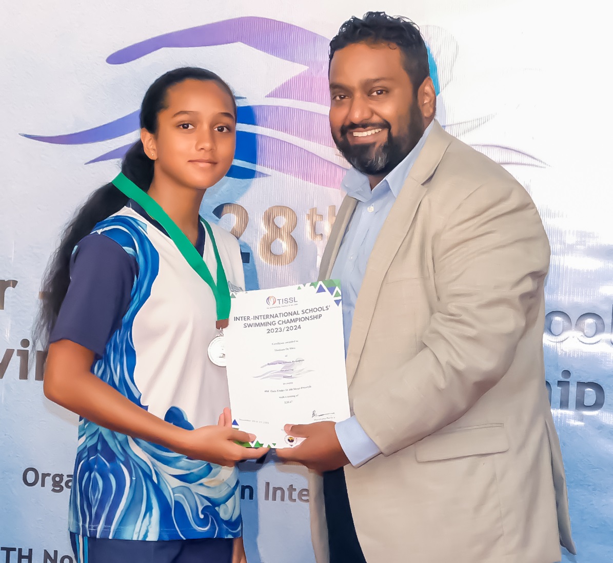 Young girl receiving swimming award from man in gray blazer at championship ceremony.