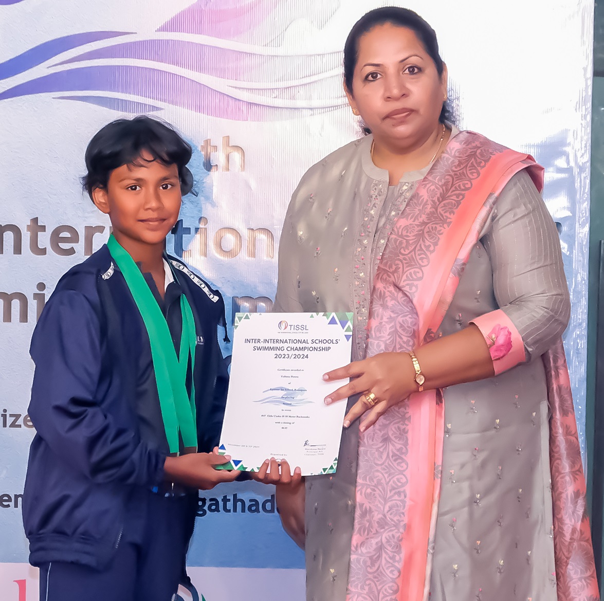 Young student receives award from teacher at international event.