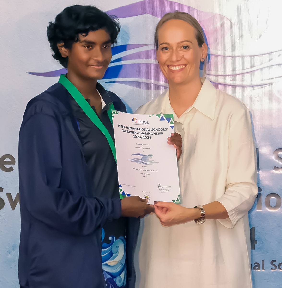 Two women smiling and holding a certificate during an award ceremony.