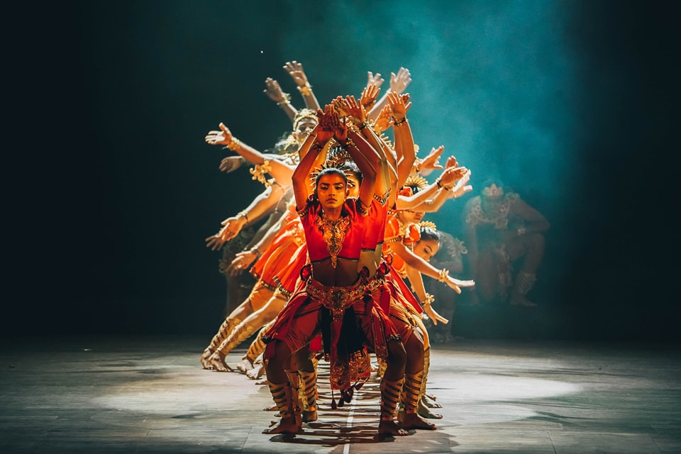 Dynamic cultural dance with central vibrant dancer and synchronized multi-armed illusion.