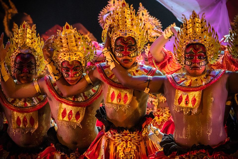 Performers in ornate gold costumes and masks in traditional cultural dance.