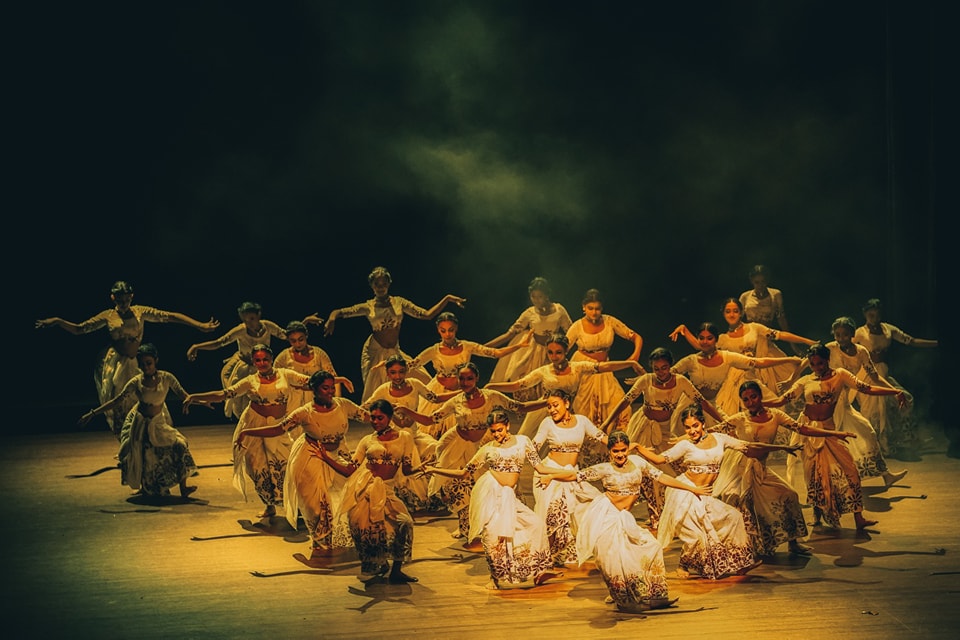 Traditional dancers perform in golden light with mist and intricate movements.