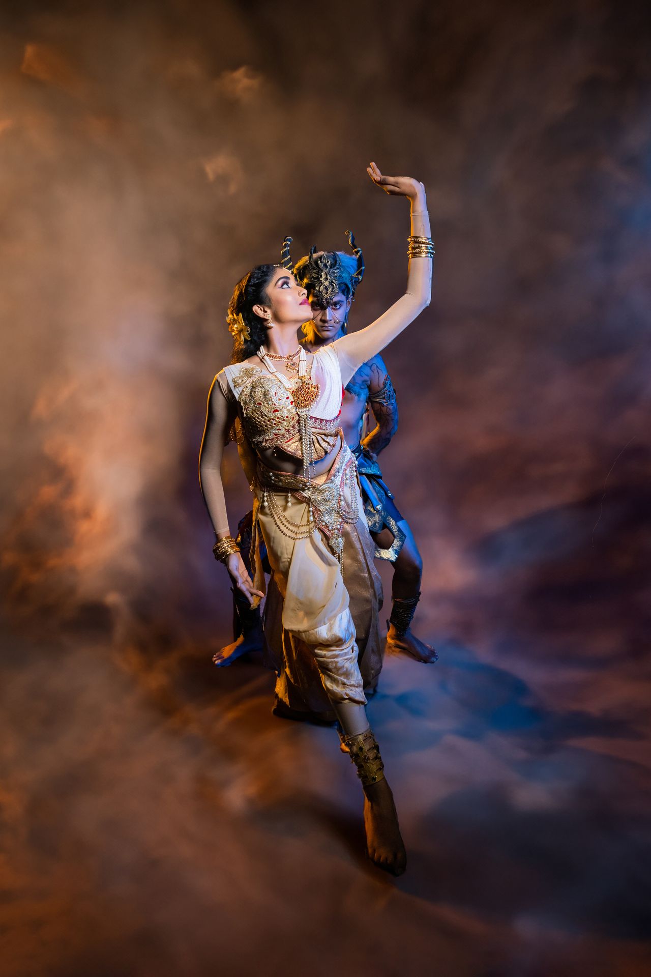 Graceful dancers in golden traditional attire, performing against a misty, dramatic backdrop.