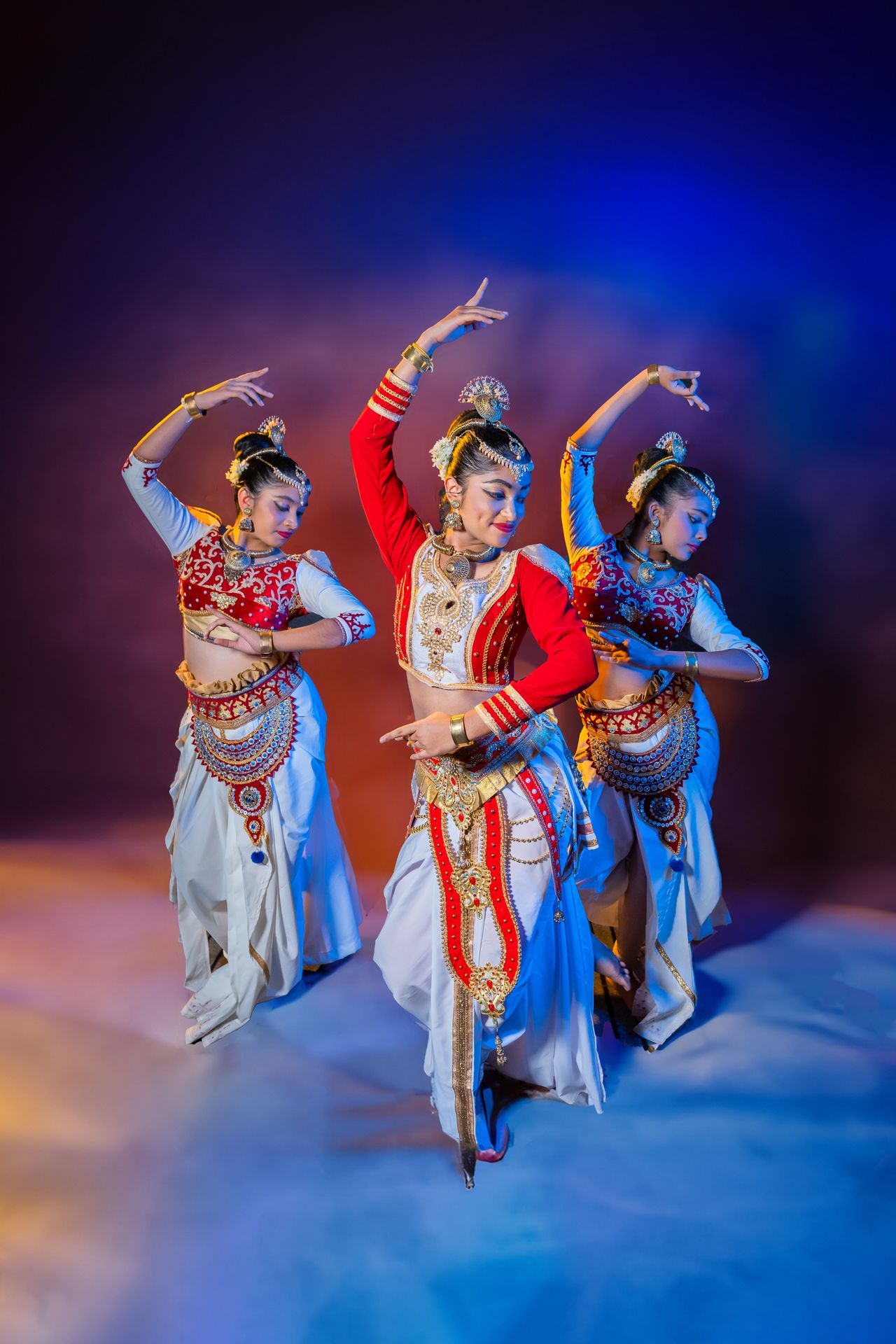 Traditional dancers in ornate costumes performing against a colorful backdrop.