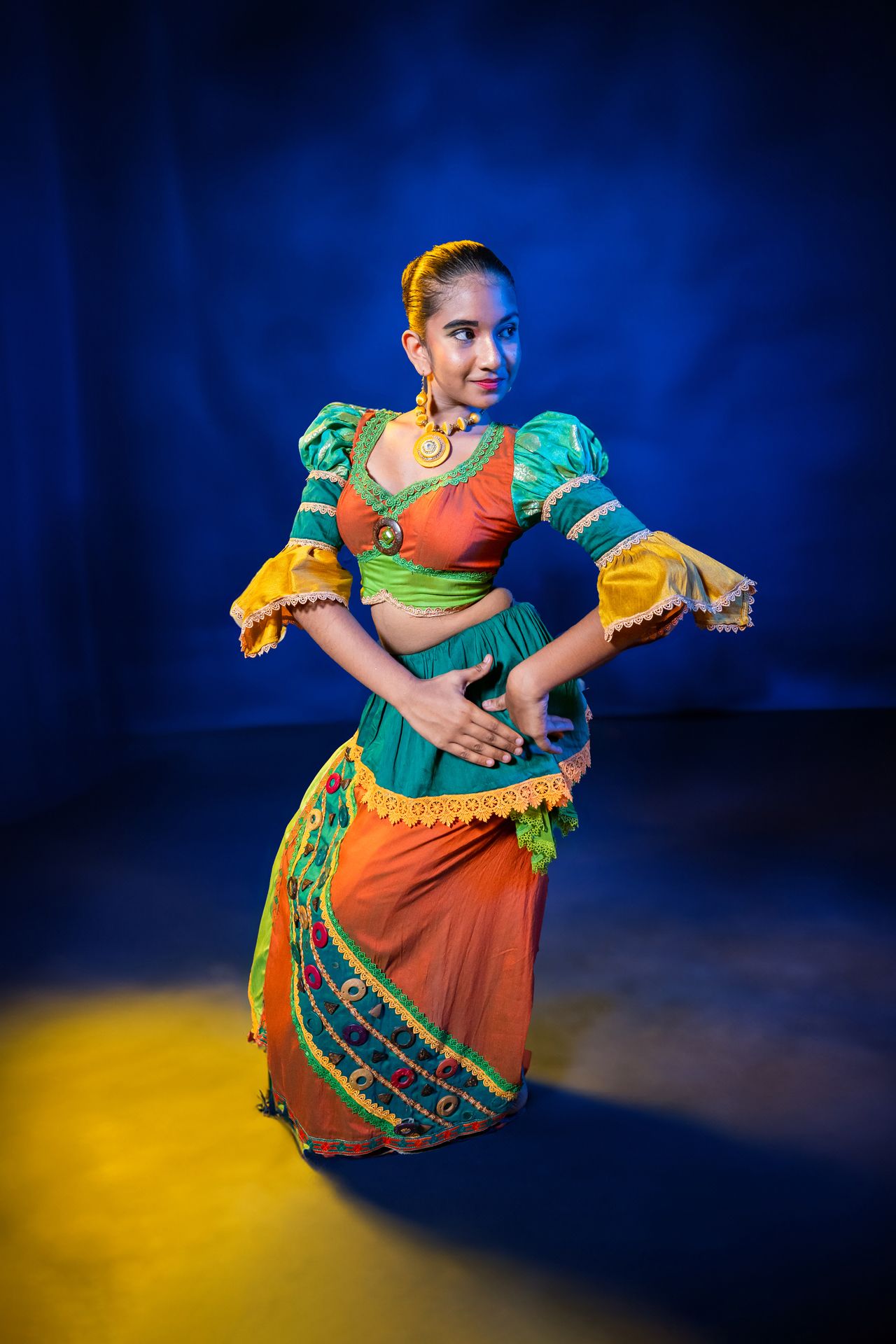 Traditional dancer in vibrant attire against a blue backdrop.