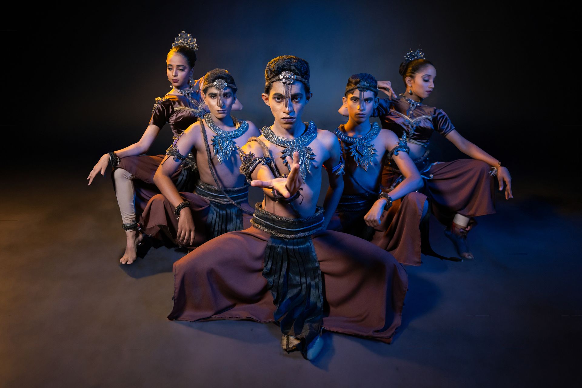 Traditional dancers in dramatic pose with rich costumes and mystical lighting.