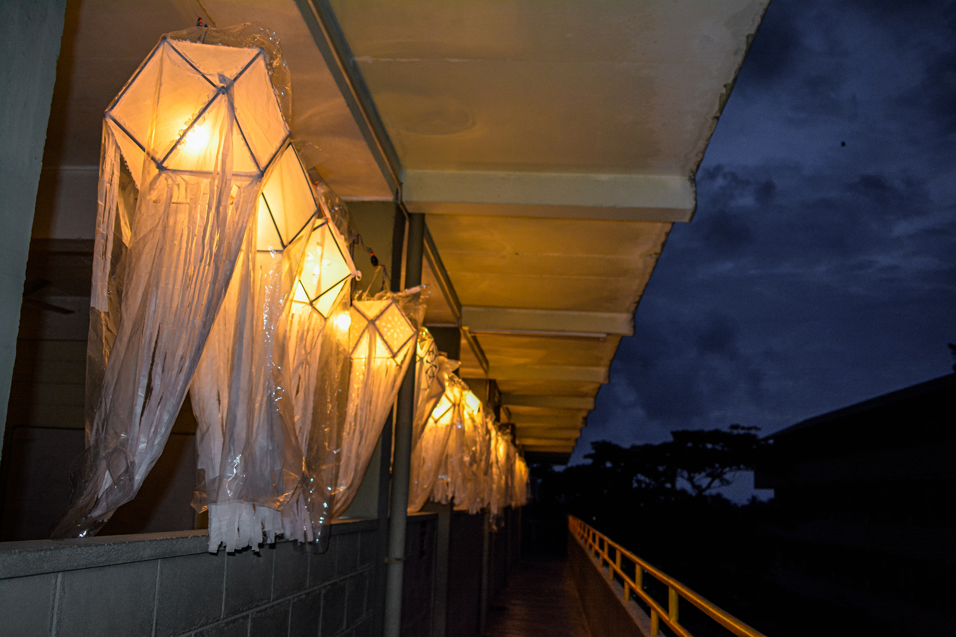 Illuminated hexagonal lanterns hanging in a serene nighttime corridor.