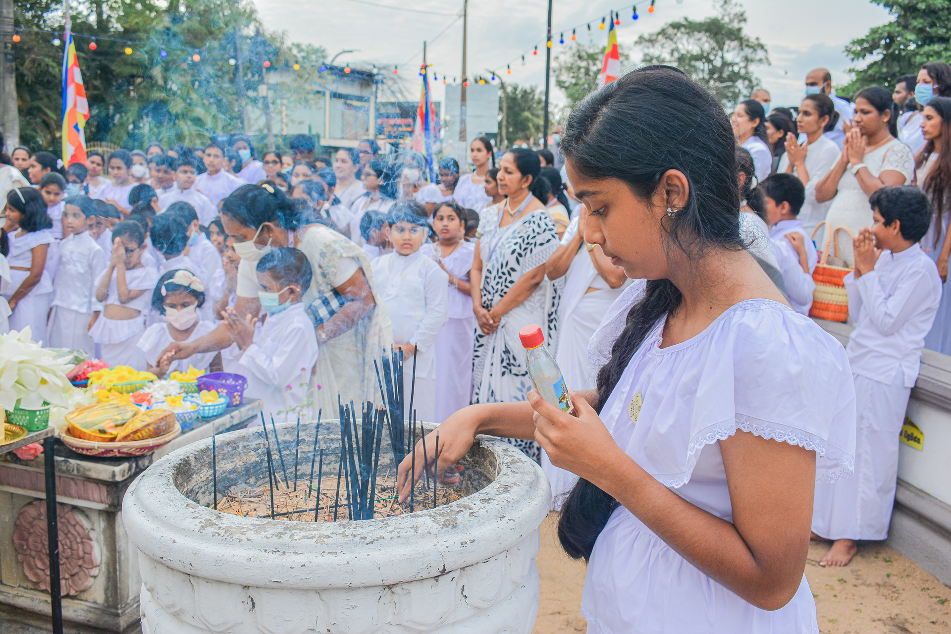 A girl places incense sticks in a burner during a communal religious ceremony.