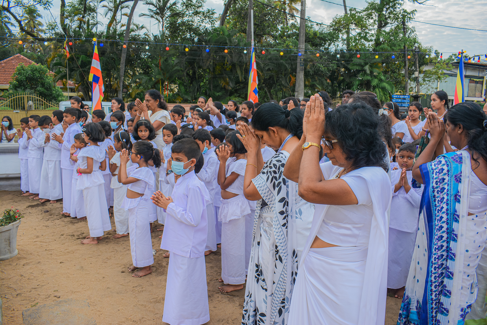 People in white attire participating in an outdoor prayer ceremony.