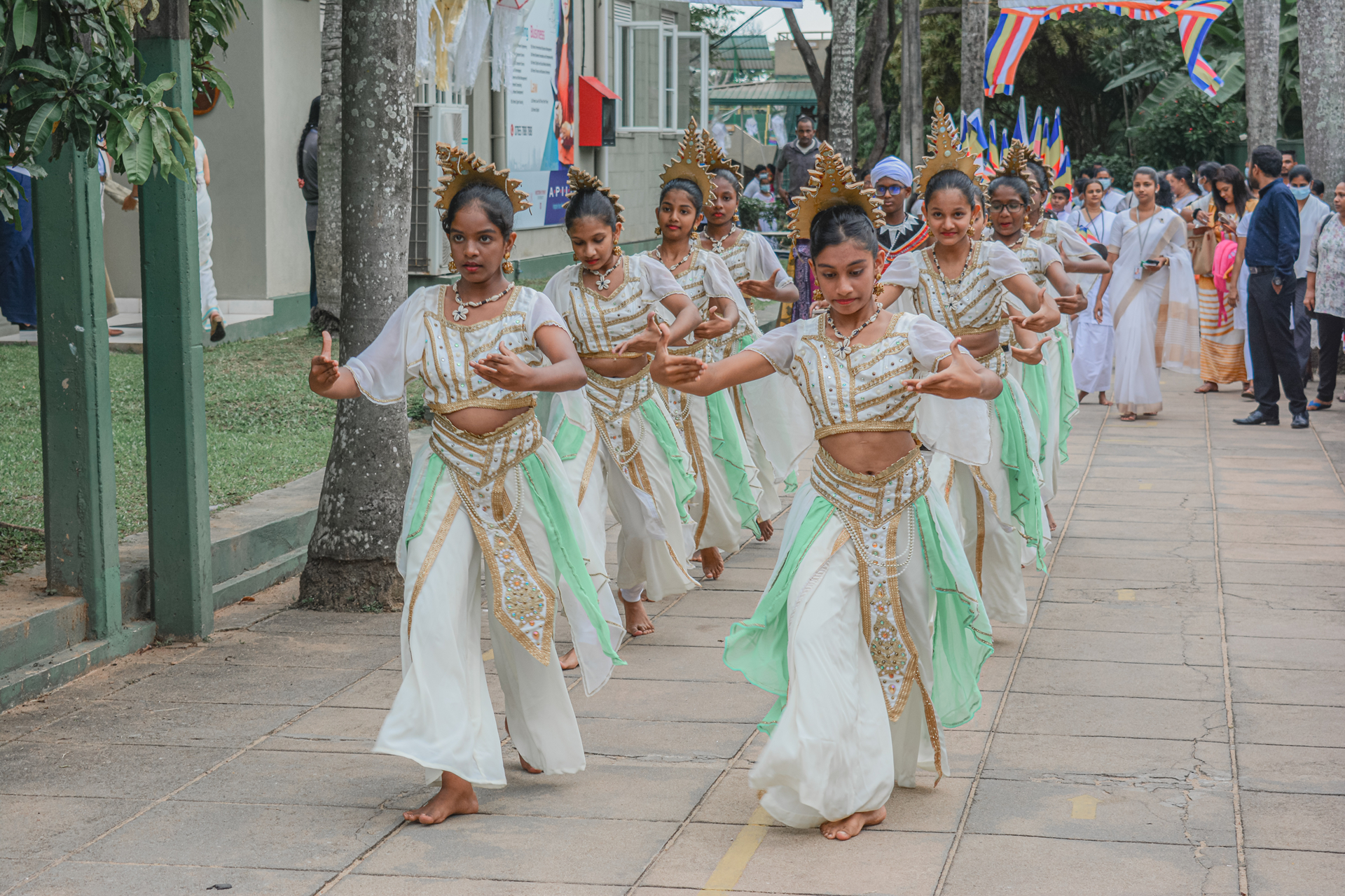 Young girls in traditional costumes perform a choreographed cultural dance outdoors.