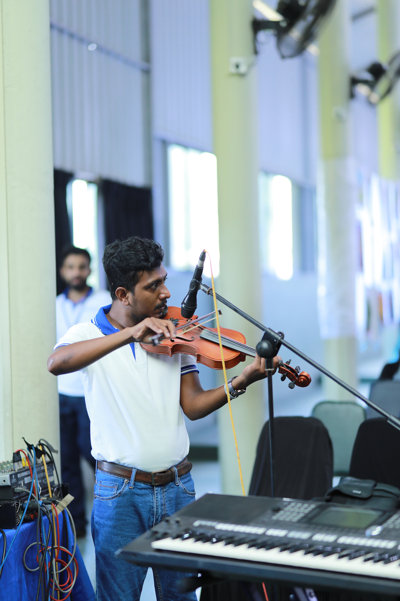 Violinist rehearsing next to a microphone in a bright, well-equipped music room.