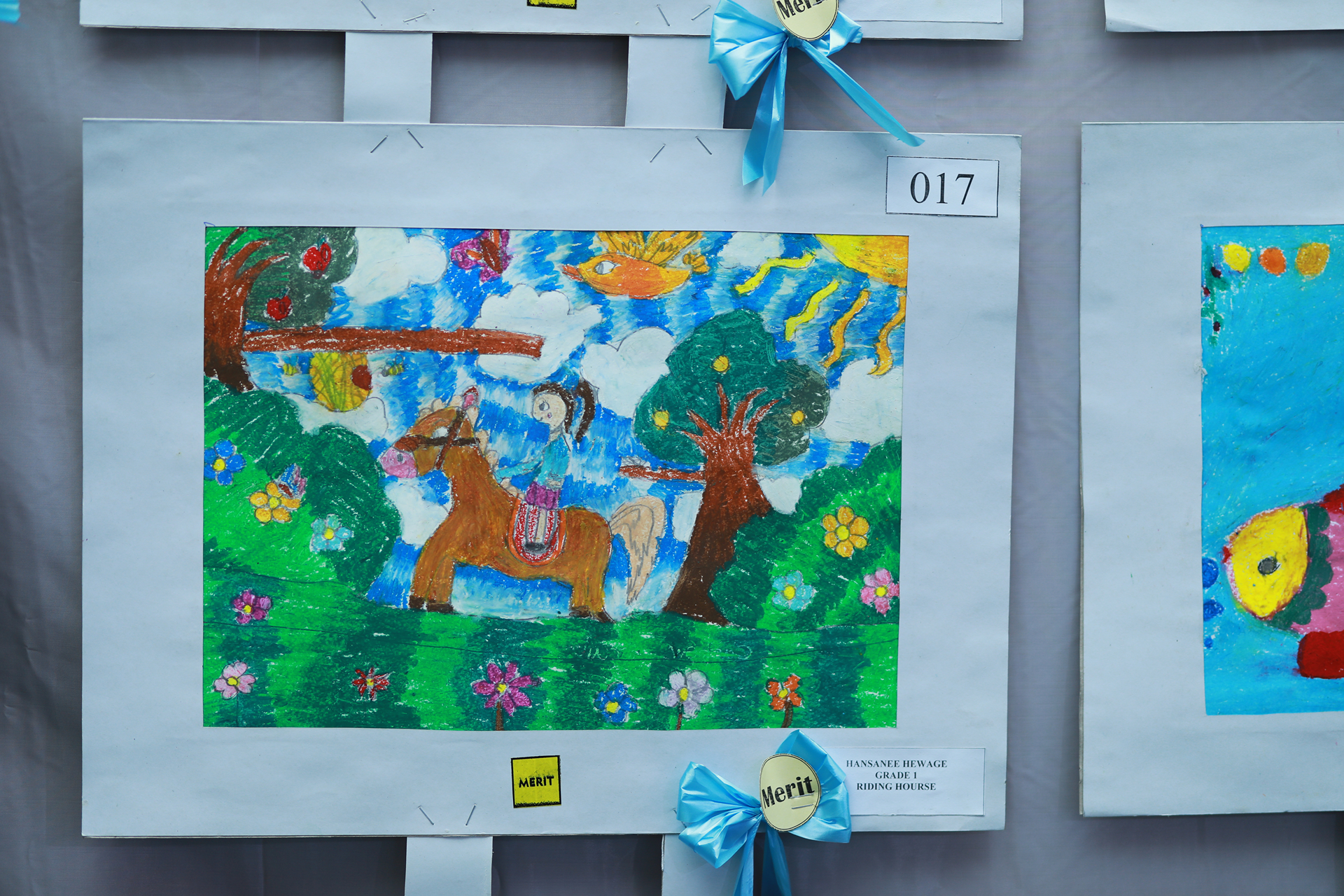 Childs colorful drawing of horse riding in nature with blue ribbon.
