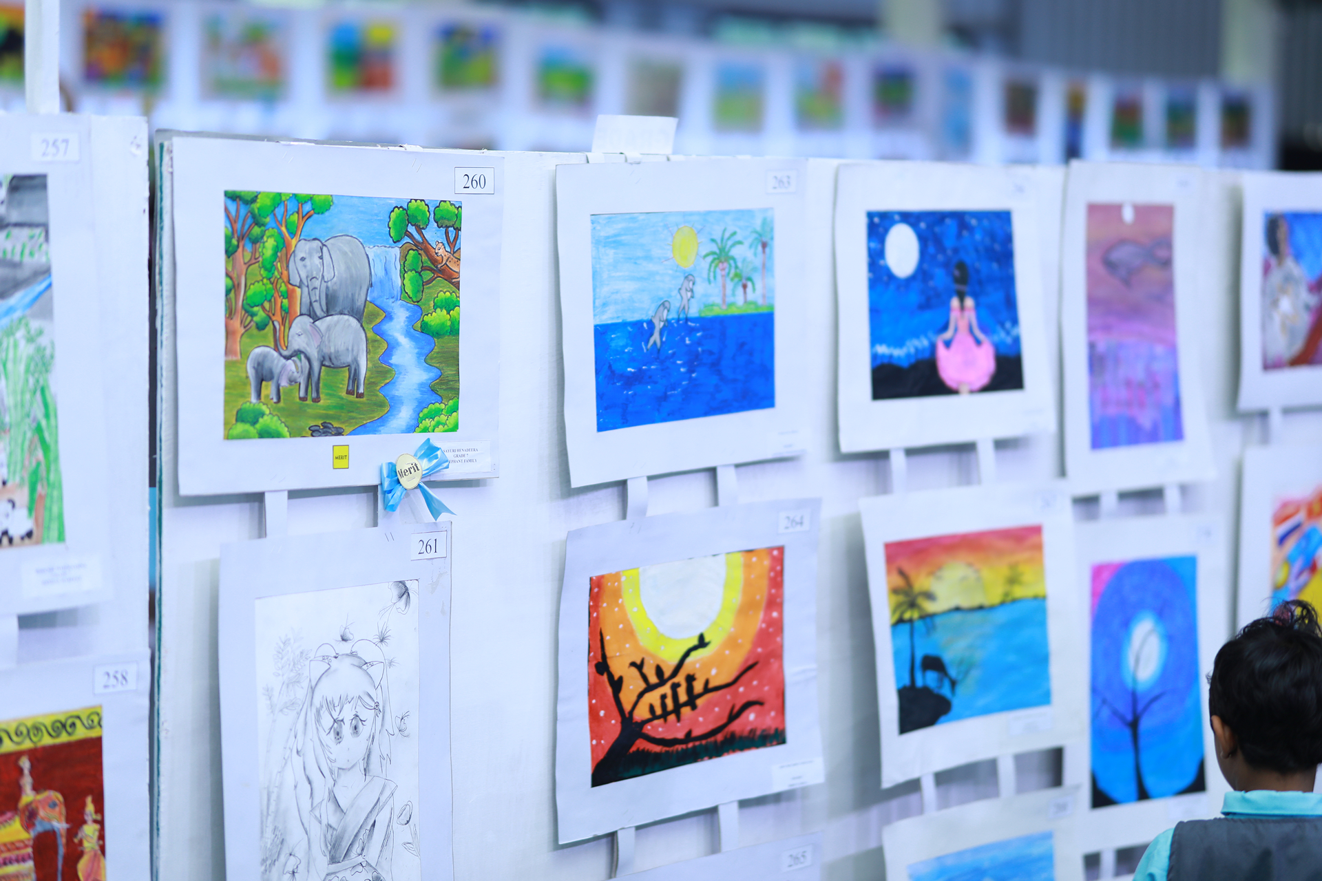 Child admiring vibrant artwork at a school exhibition.
