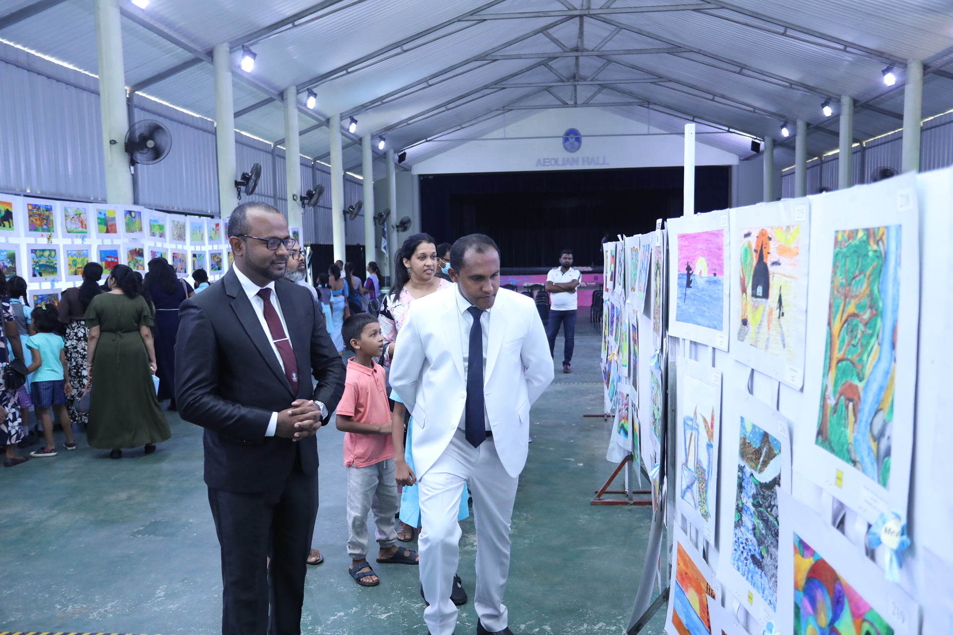 Art enthusiasts explore diverse artworks in a bright, spacious exhibition hall.