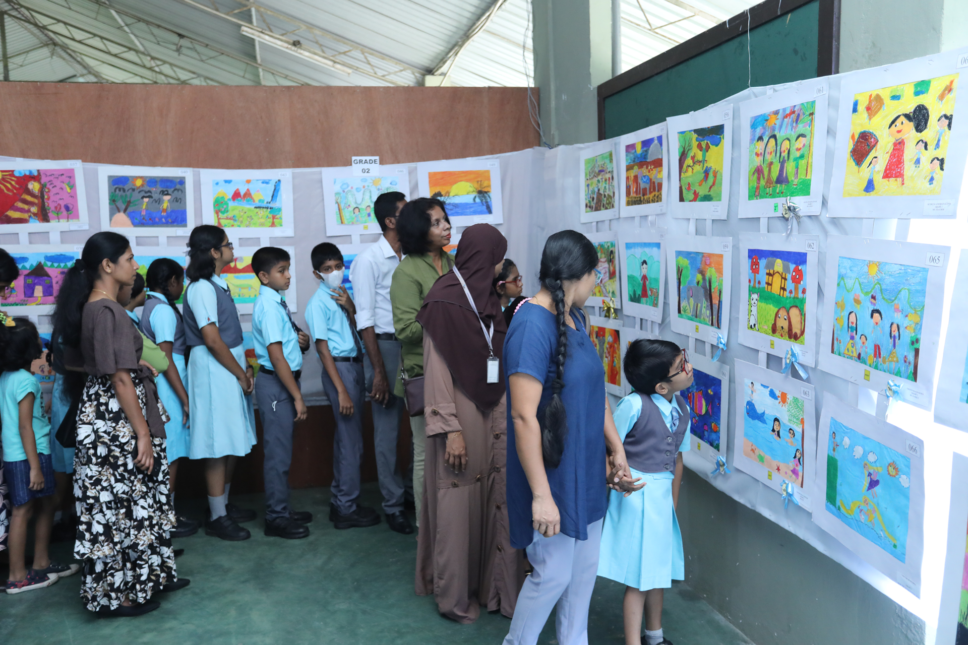 Children and adults admiring colorful drawings at an art exhibition.