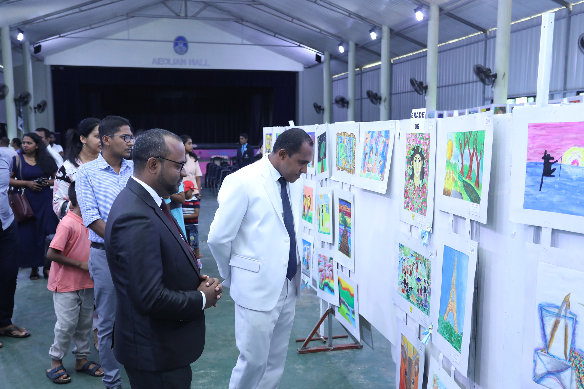 Modern art exhibition with visitors examining colorful paintings in a spacious gallery.