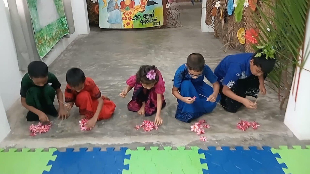Children in traditional outfits sorting flower petals during a cultural celebration.