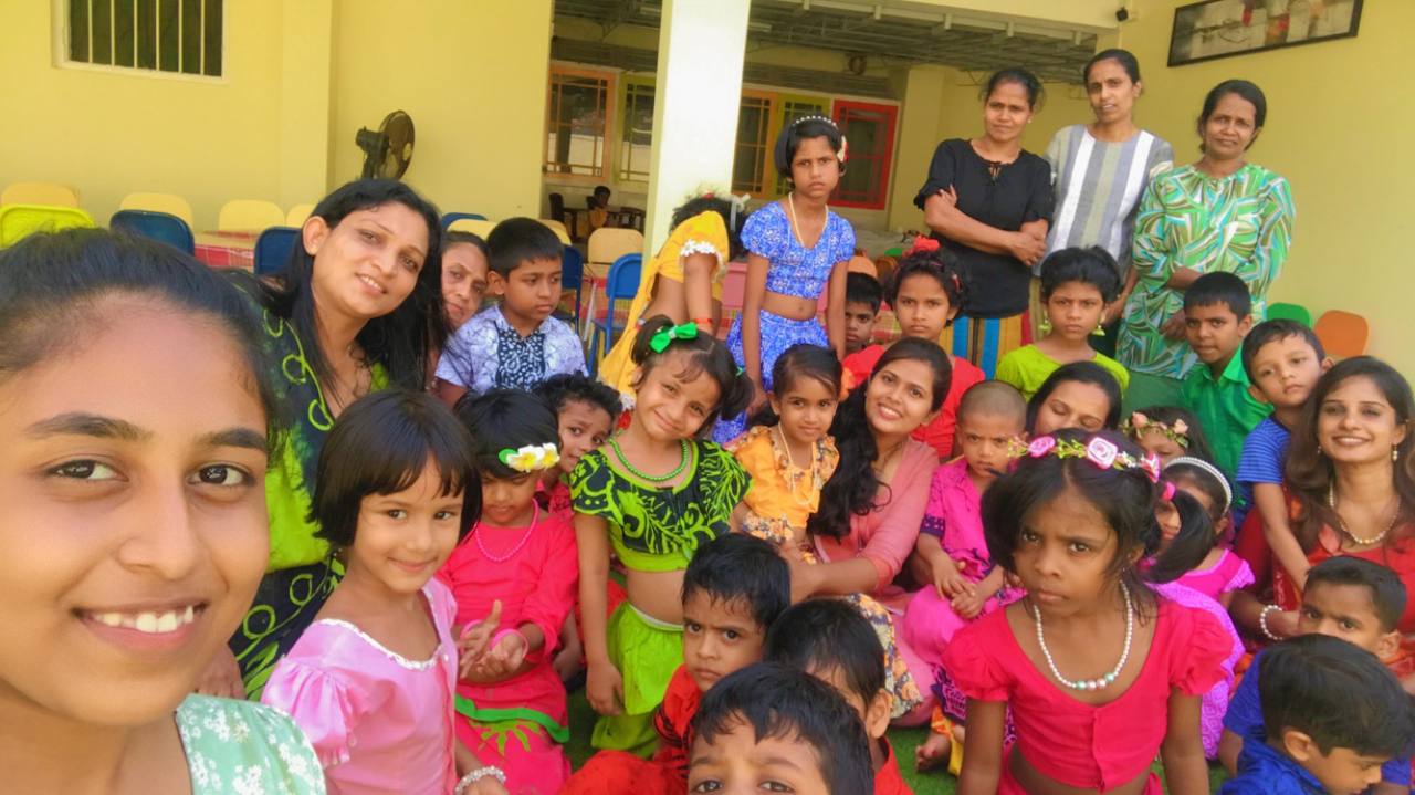 Children and adults in colorful traditional attire celebrating outdoors.