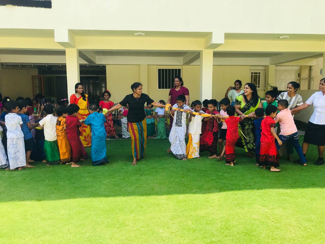 Children and adults enjoying a colorful outdoor cultural celebration on a sunny day.