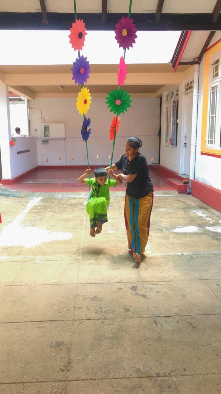 Generations of joy: Child swinging with older woman in colorful courtyard.