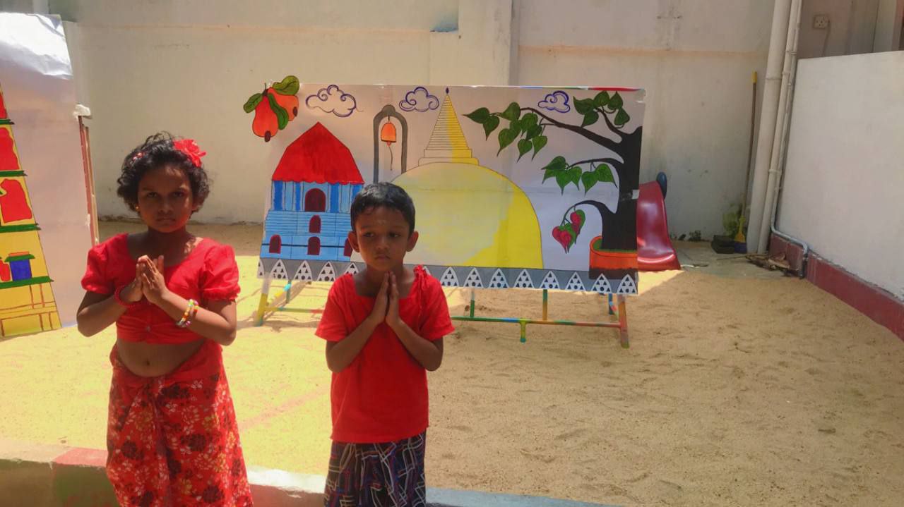 Children in traditional attire at a colorful schoolyard celebration.