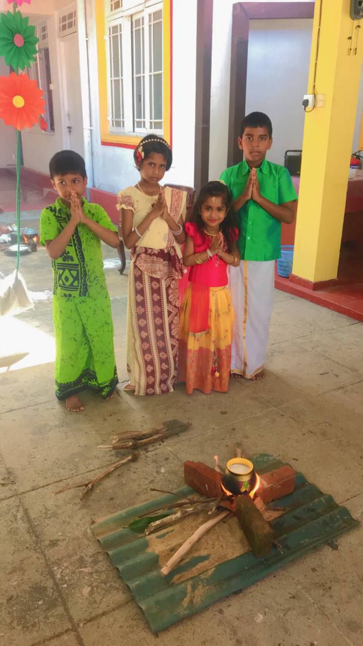 Children in traditional attire celebrating a cultural festival indoors with decorations and ritual items.