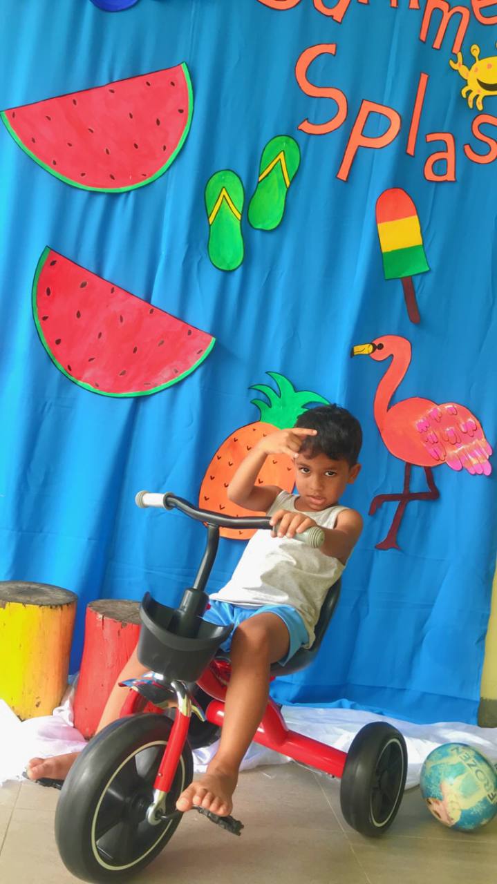Child on a tricycle with a vibrant summer-themed backdrop.