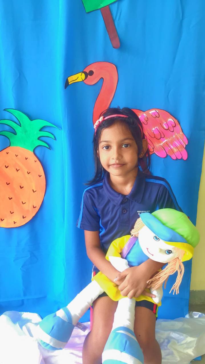 Young girl in uniform holding a colorful doll with a vibrant backdrop.