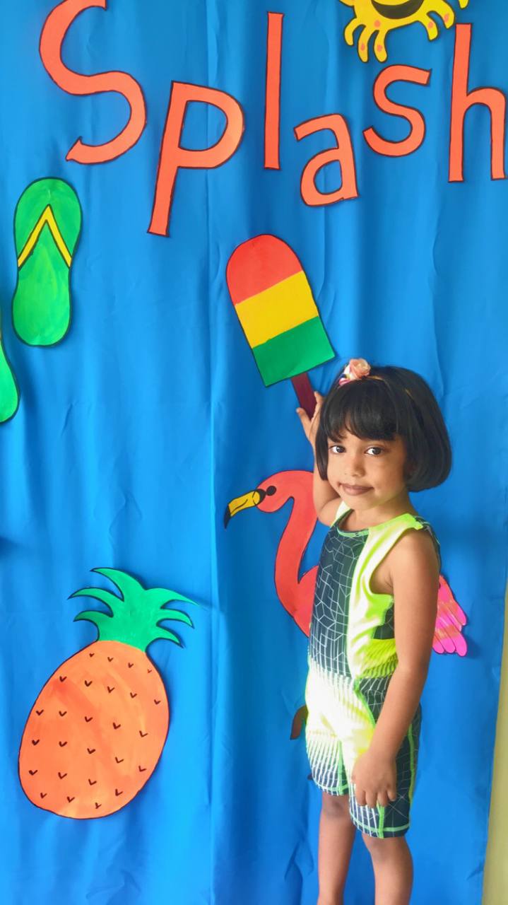 Child at vibrant summer splash party with colorful decorations and a rainbow popsicle cut-out.