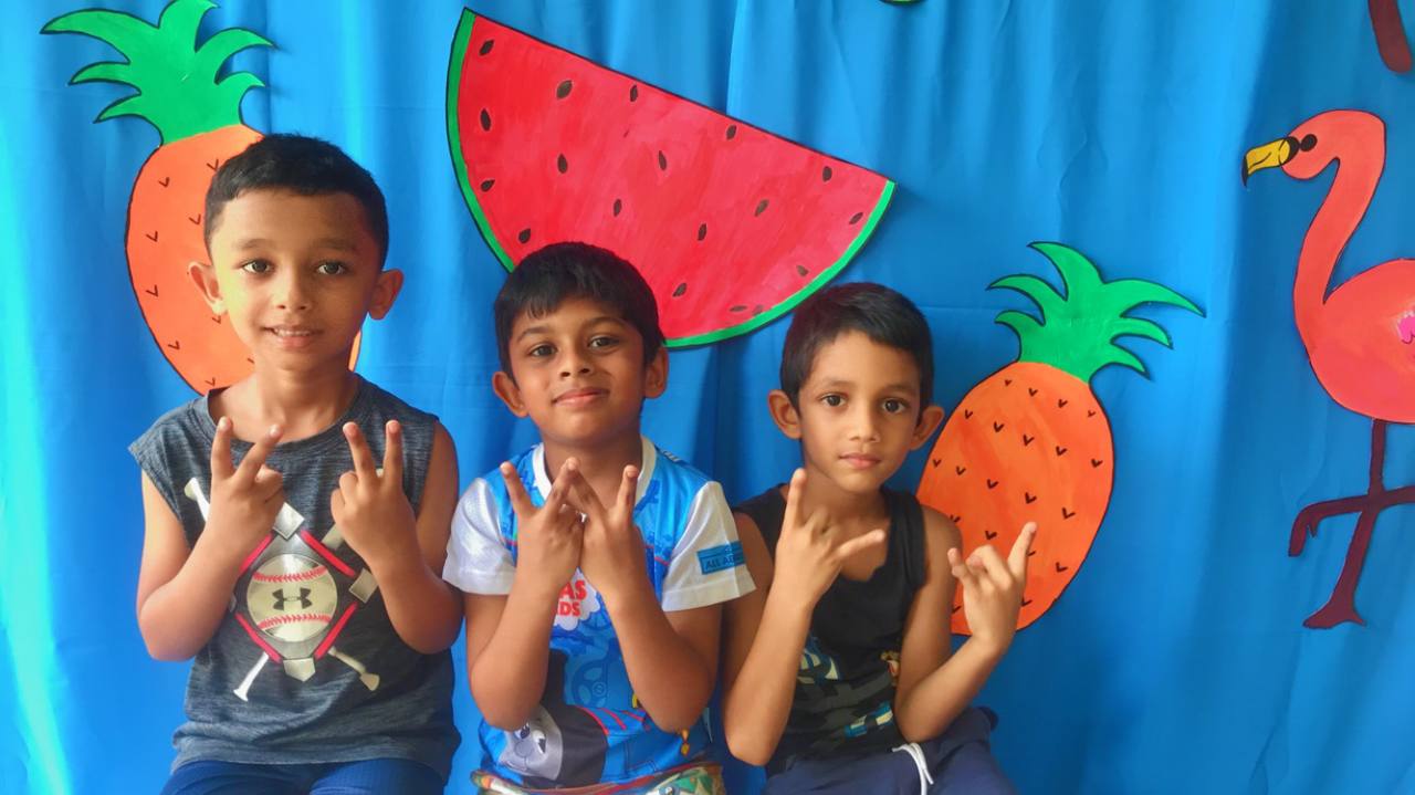 Boys happily posing in front of a colorful, tropical-themed party backdrop.