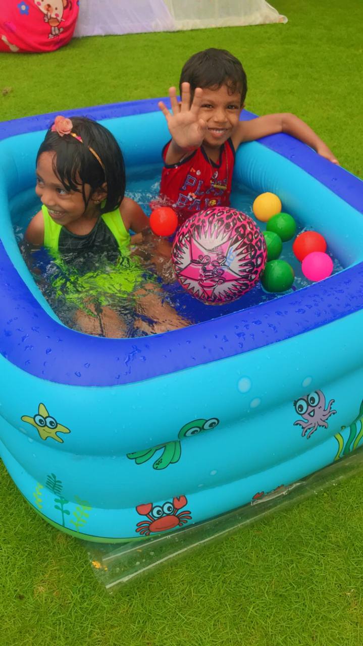 Kids enjoying a colorful inflatable pool with floating balls on a sunny day.
