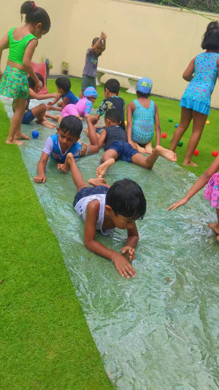 Children playing on a homemade slip-and-slide on a sunny lawn.