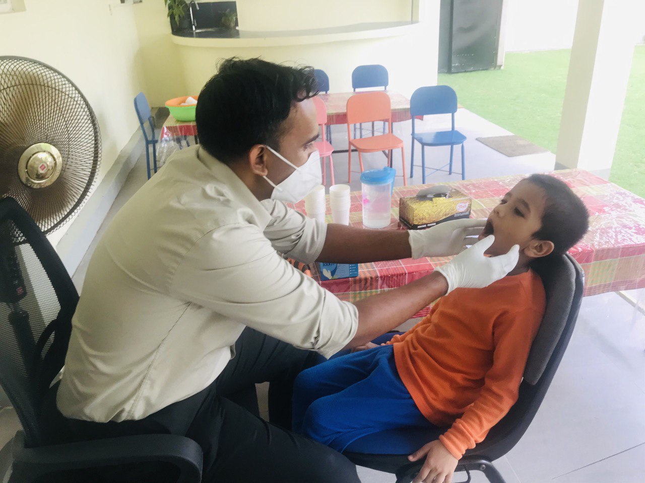 Child receiving a check-up from a masked healthcare worker in a school setting.