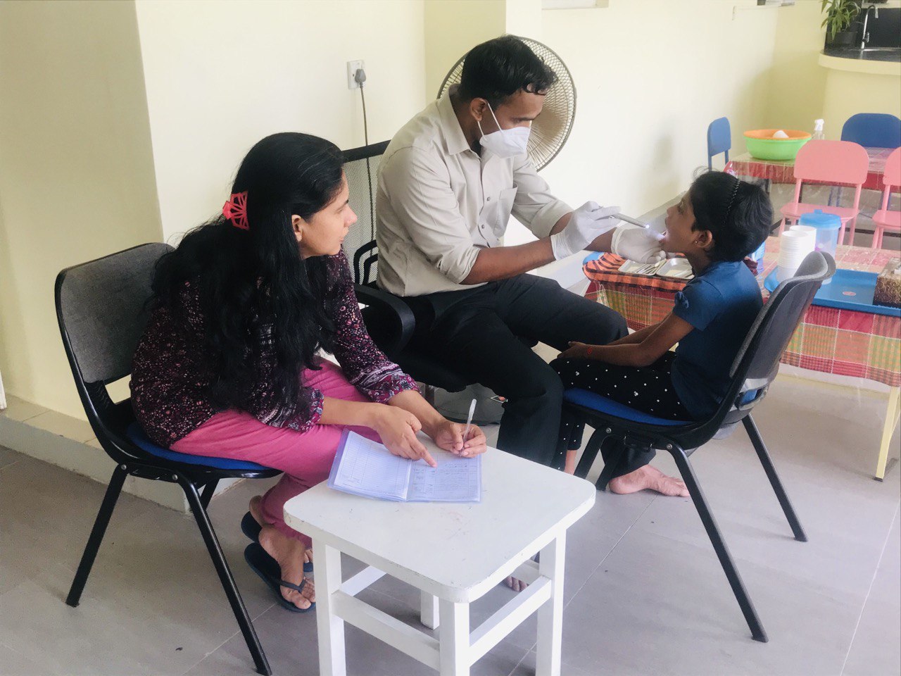 Pediatrician examines childs throat as guardian observes in colorful clinic.