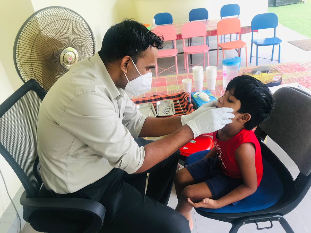 Healthcare professional examines boys mouth in a child-friendly clinic.