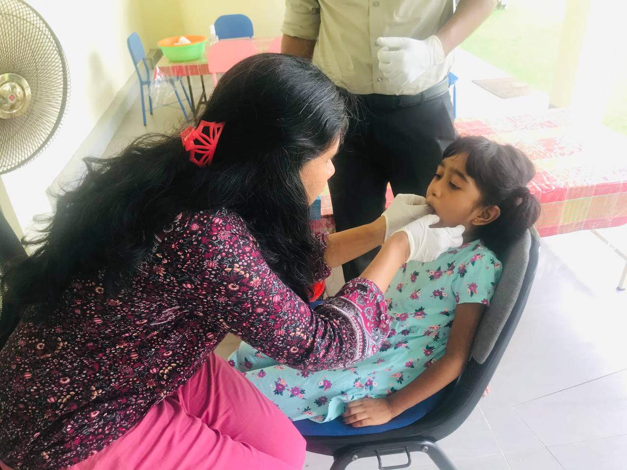Woman examines childs mouth during dental check-up in a community clinic setting.