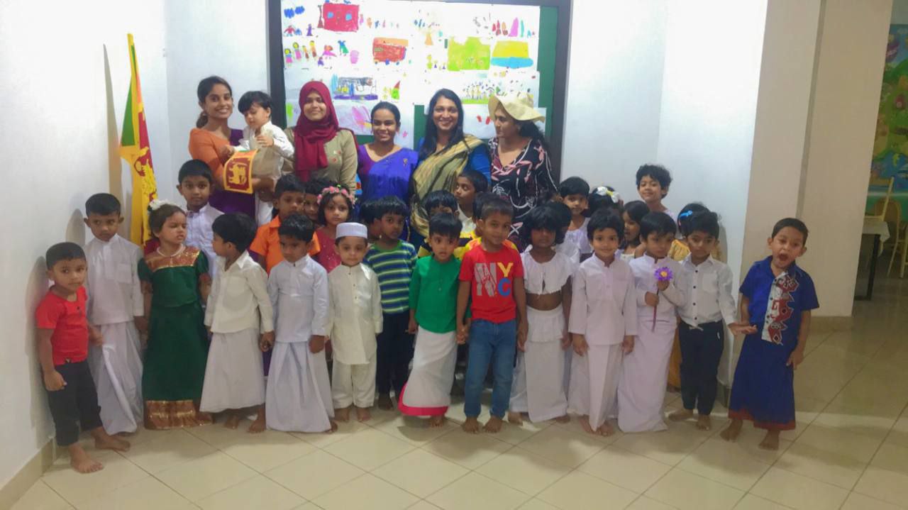 Children and adults celebrating cultural event in traditional attire indoors.