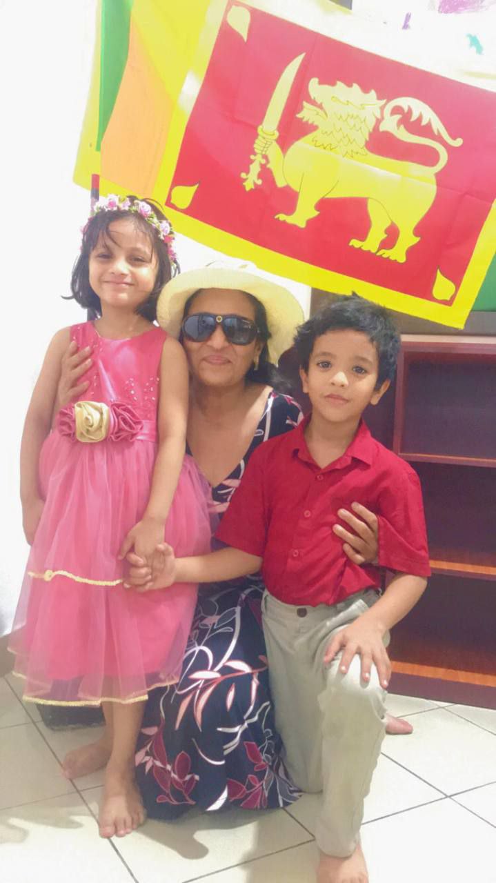 Family posing happily in front of a colorful cultural flag.