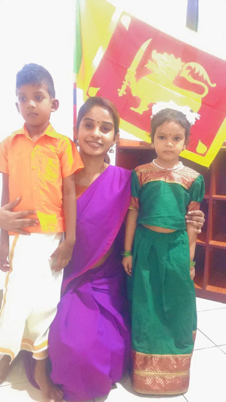 Family in traditional Sri Lankan attire with national flag.