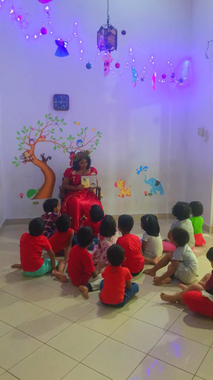 Teacher reading to children in a colorful, decorated classroom.