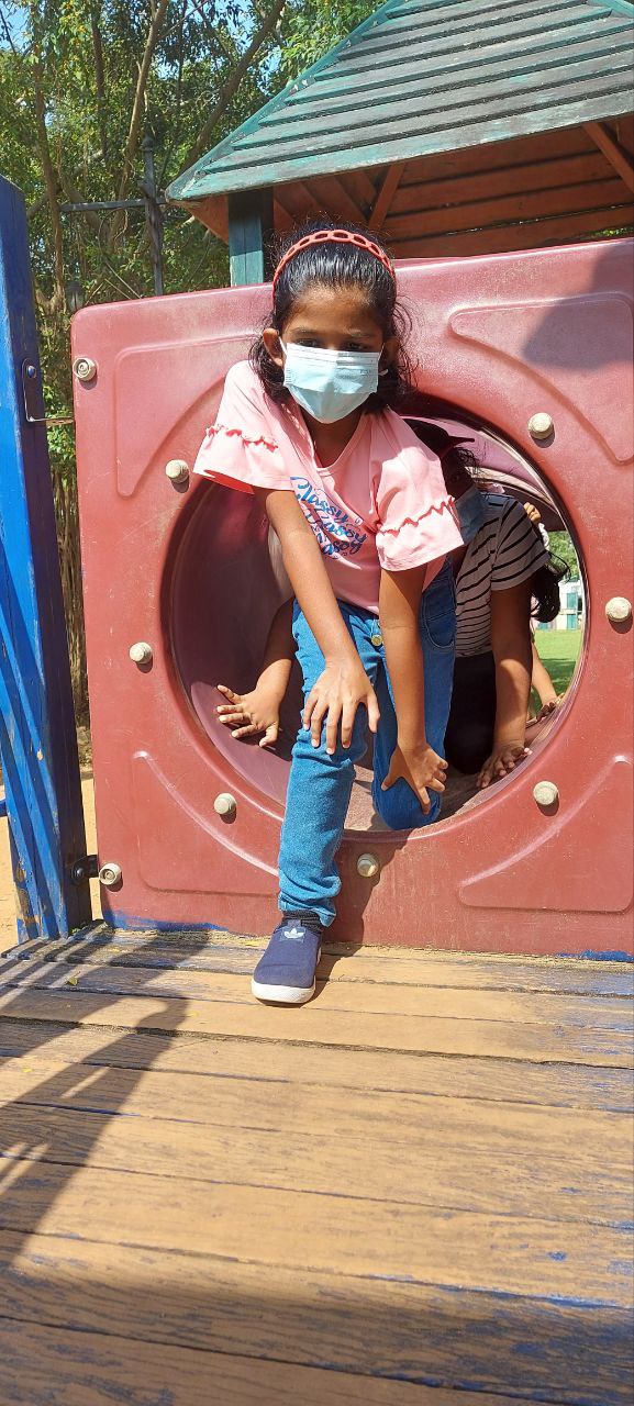 Girl in mask playing on outdoor playground.