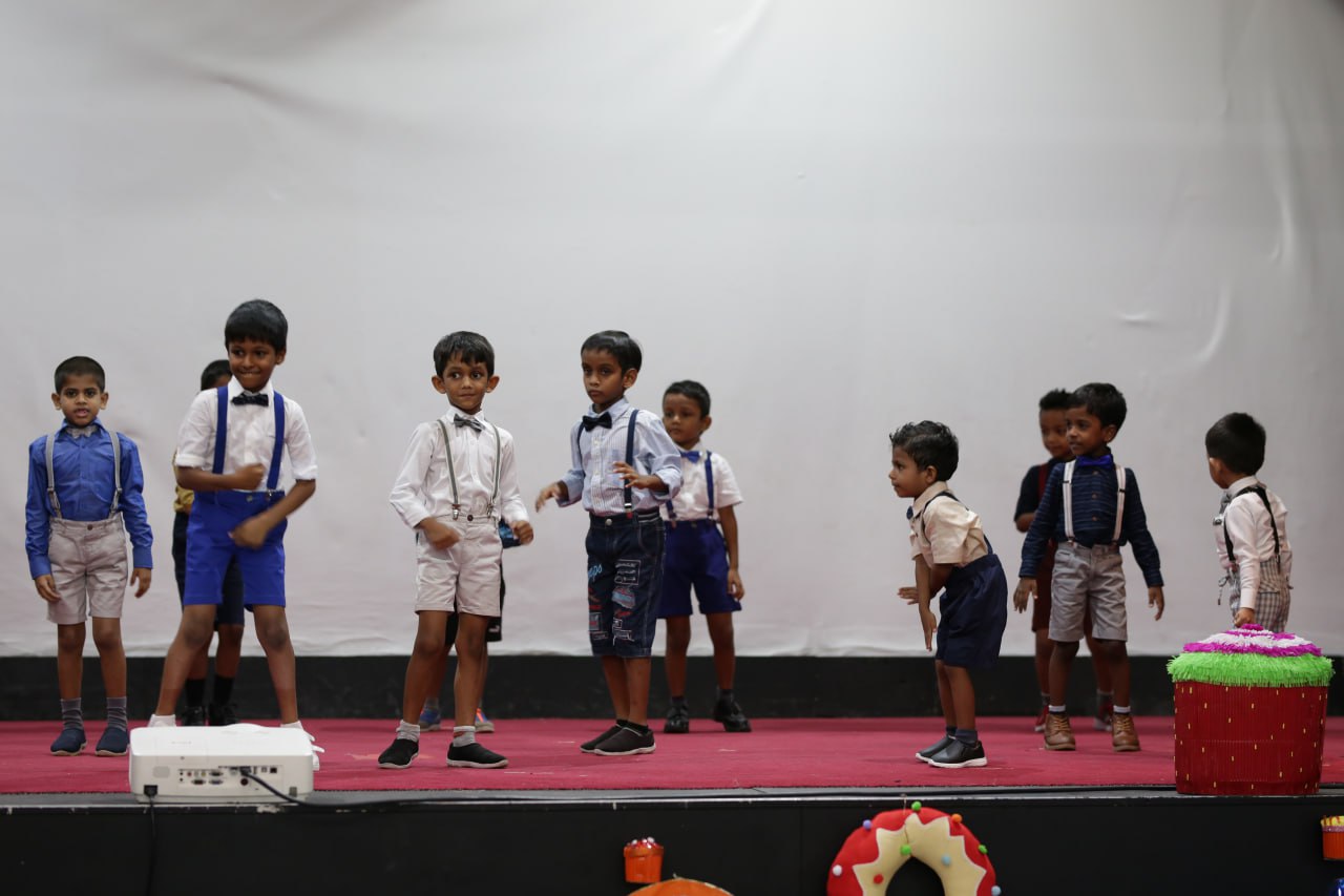 Young boys rehearsing on a red-carpeted stage with festive decorations.