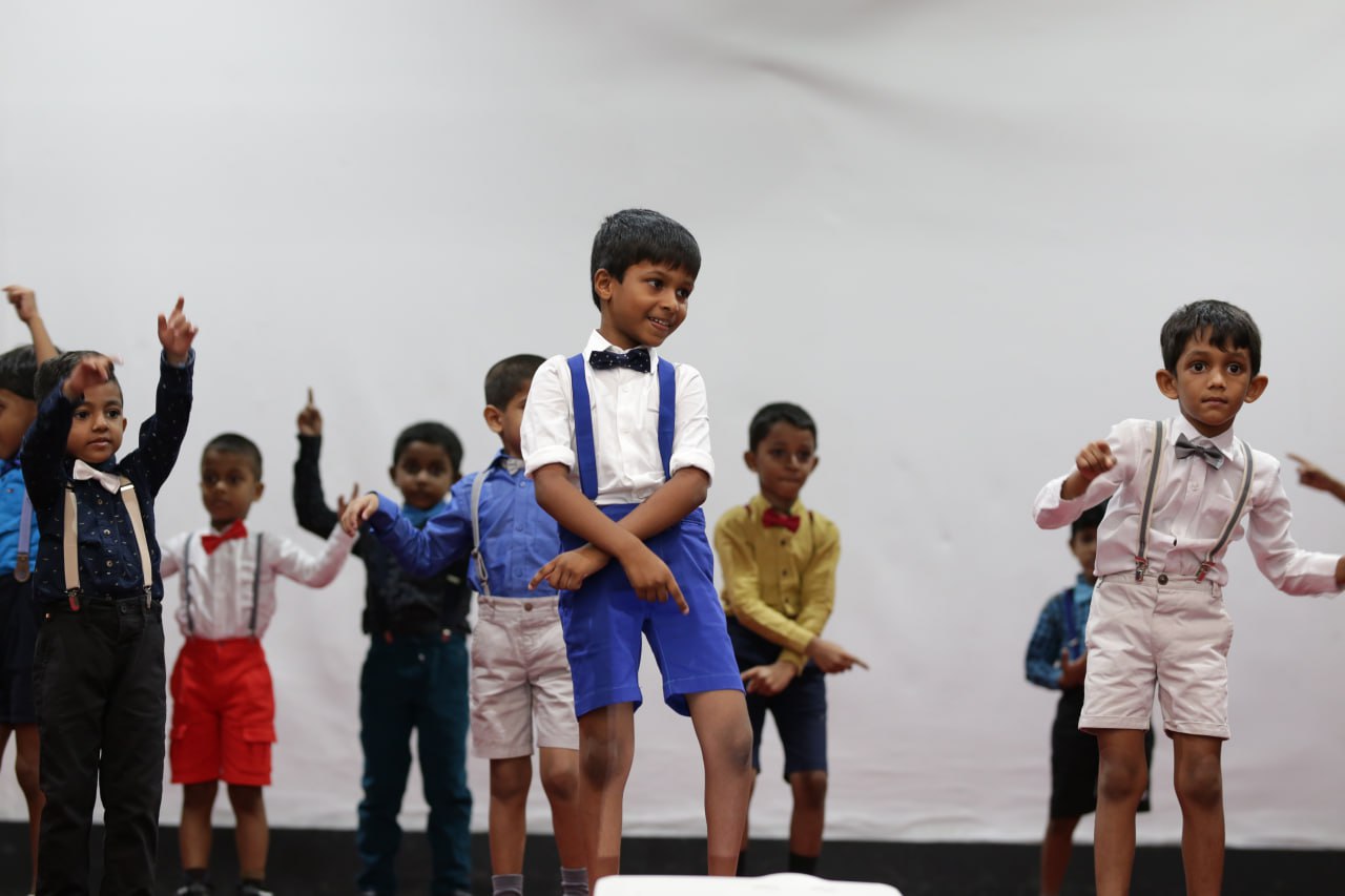 Young boys performing a lively dance in colorful outfits on stage.