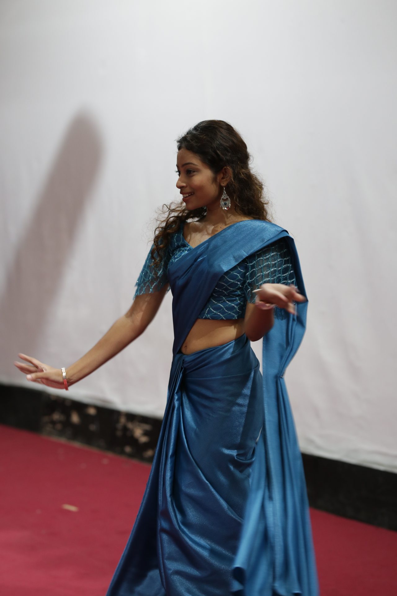 Young woman in a blue silk sari, dancing gracefully.