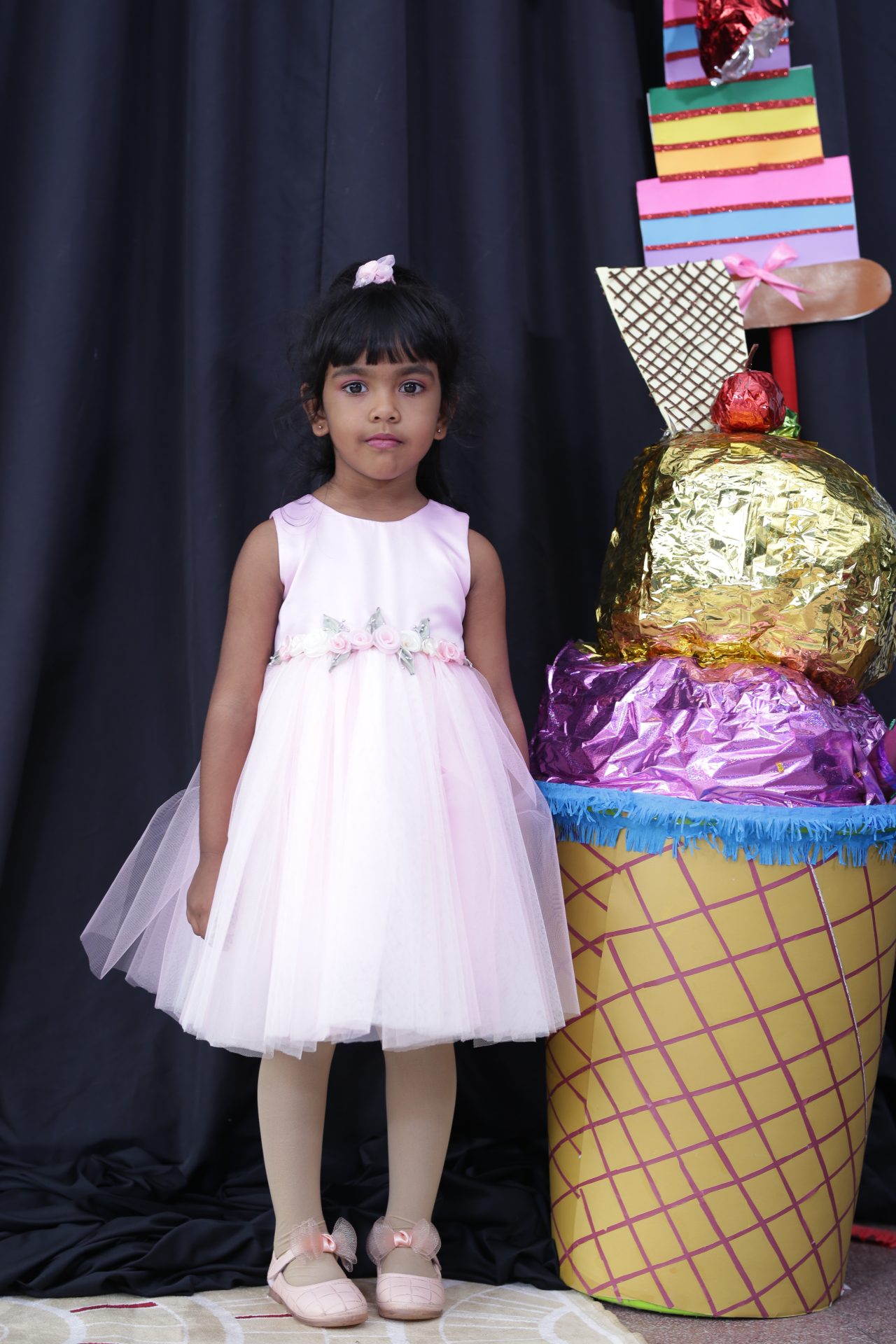 Young girl in white tulle dress with large colorful ice cream cone prop.