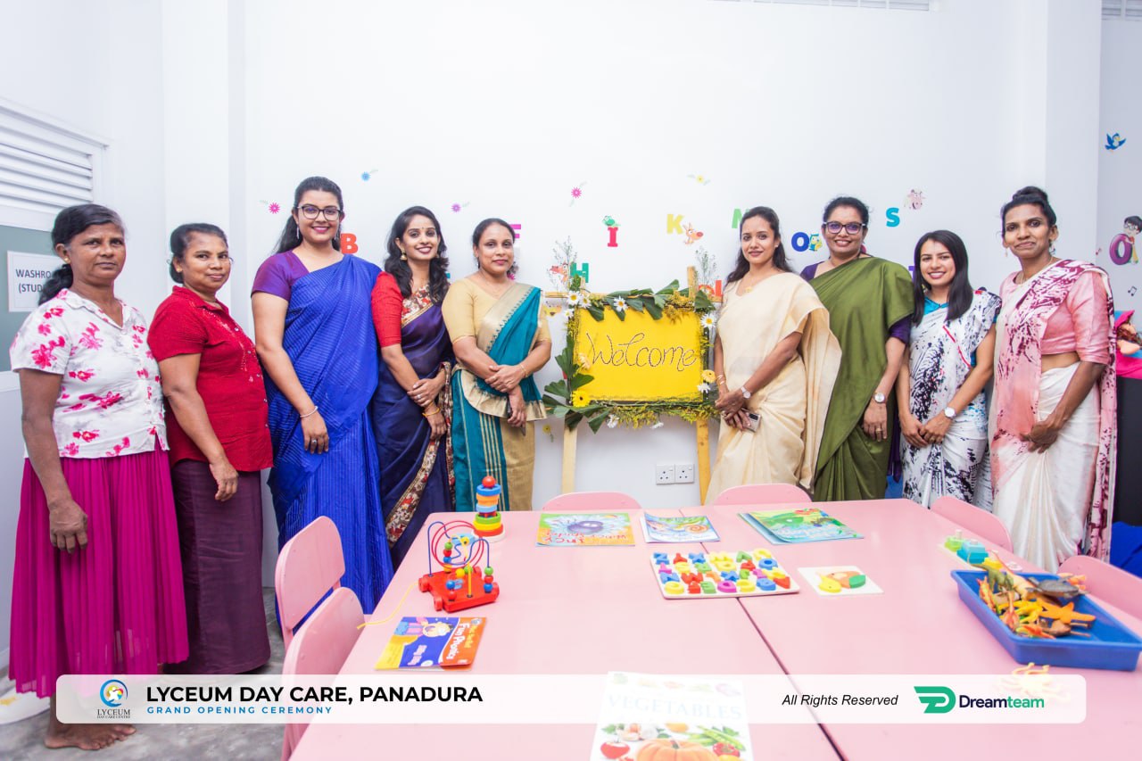 Nine women in colorful sarees at Lyceum Day Care grand opening, toys and welcome sign visible.