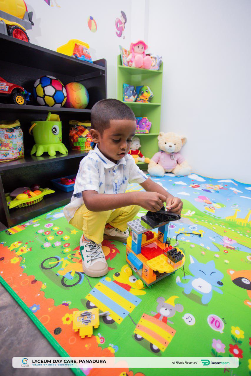 Child playing with toy blocks on colorful mat in vibrant, organized playroom.