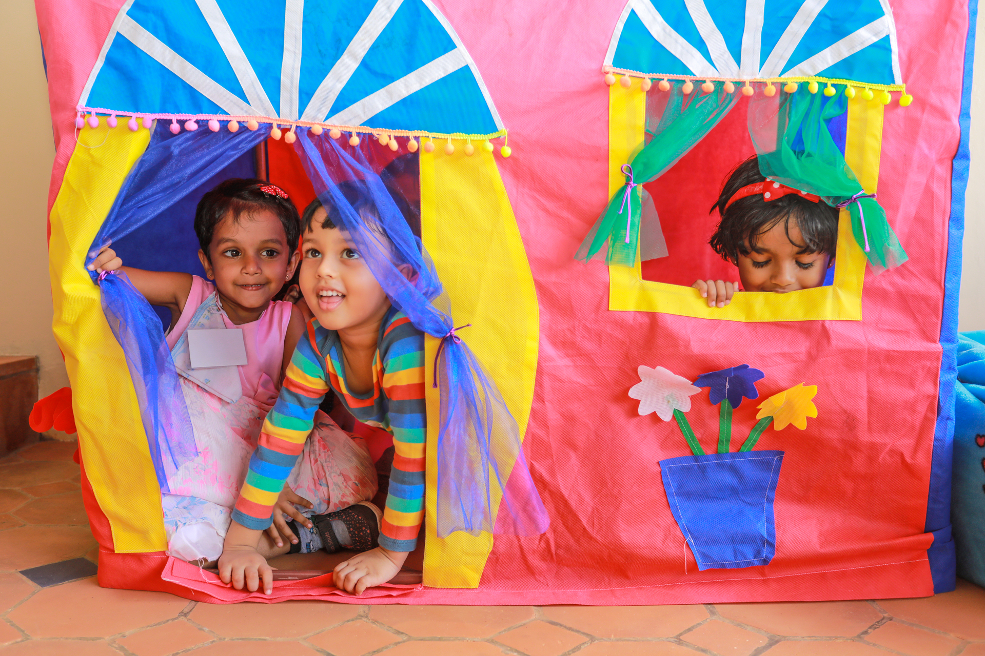 Children playing in a vibrant fabric playhouse with colorful accents.
