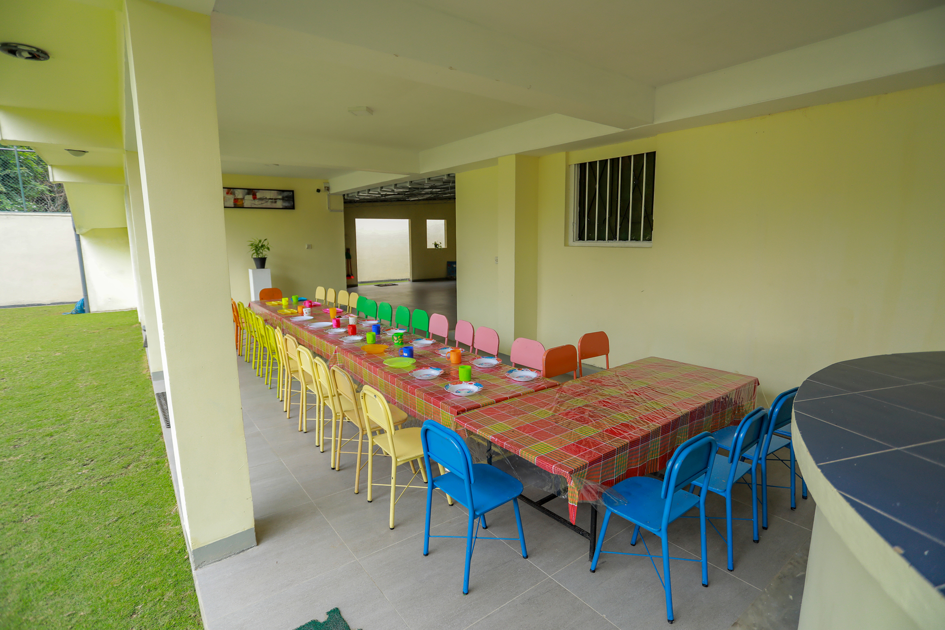 Colorful outdoor dining setup with long table and vibrant chairs for festive gathering.
